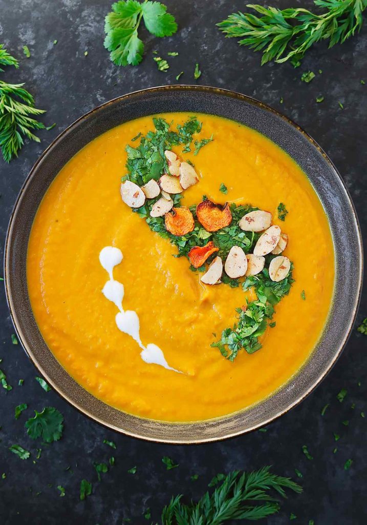 A dark grey bowl filled with Carrot Turmeric Miso Soup.