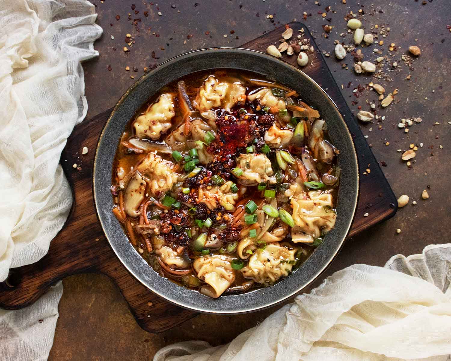 Potsticker Soup in a gray bowl on a wooden serving board.