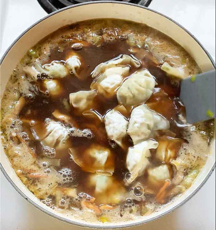 Add the soy sauce and frozen potstickers to the simmering broth.