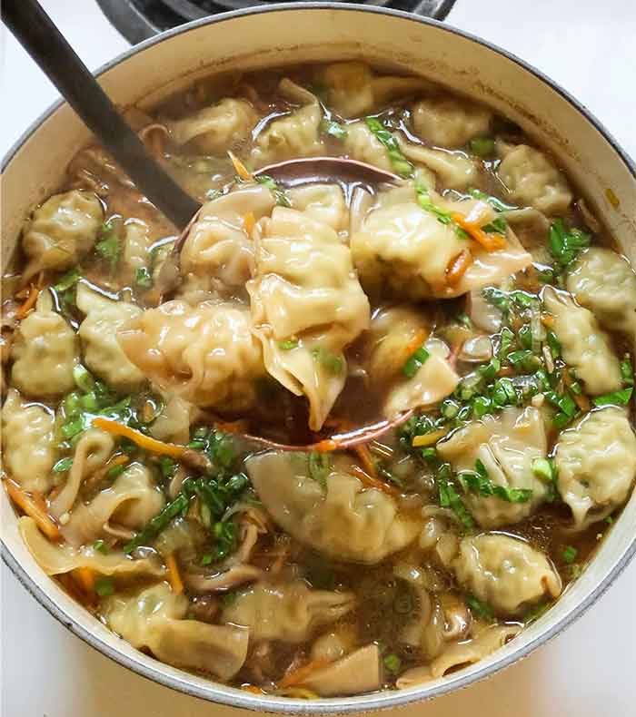 Close-up of a copper ladle filled with the soup dumplings.