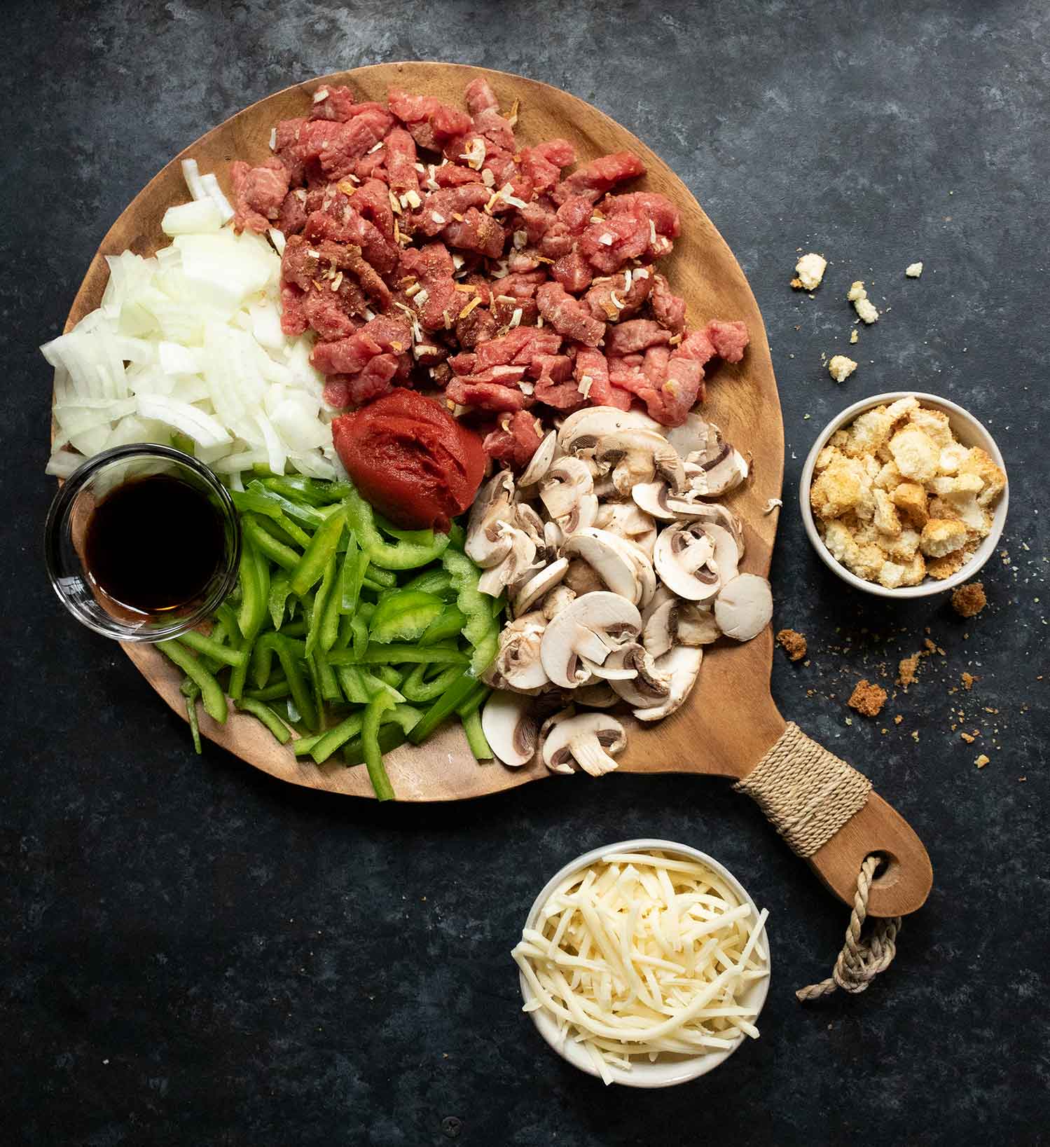 The raw ingredients of Philly Cheesesteak Soup arranged on a round serving board, ready for cooking.