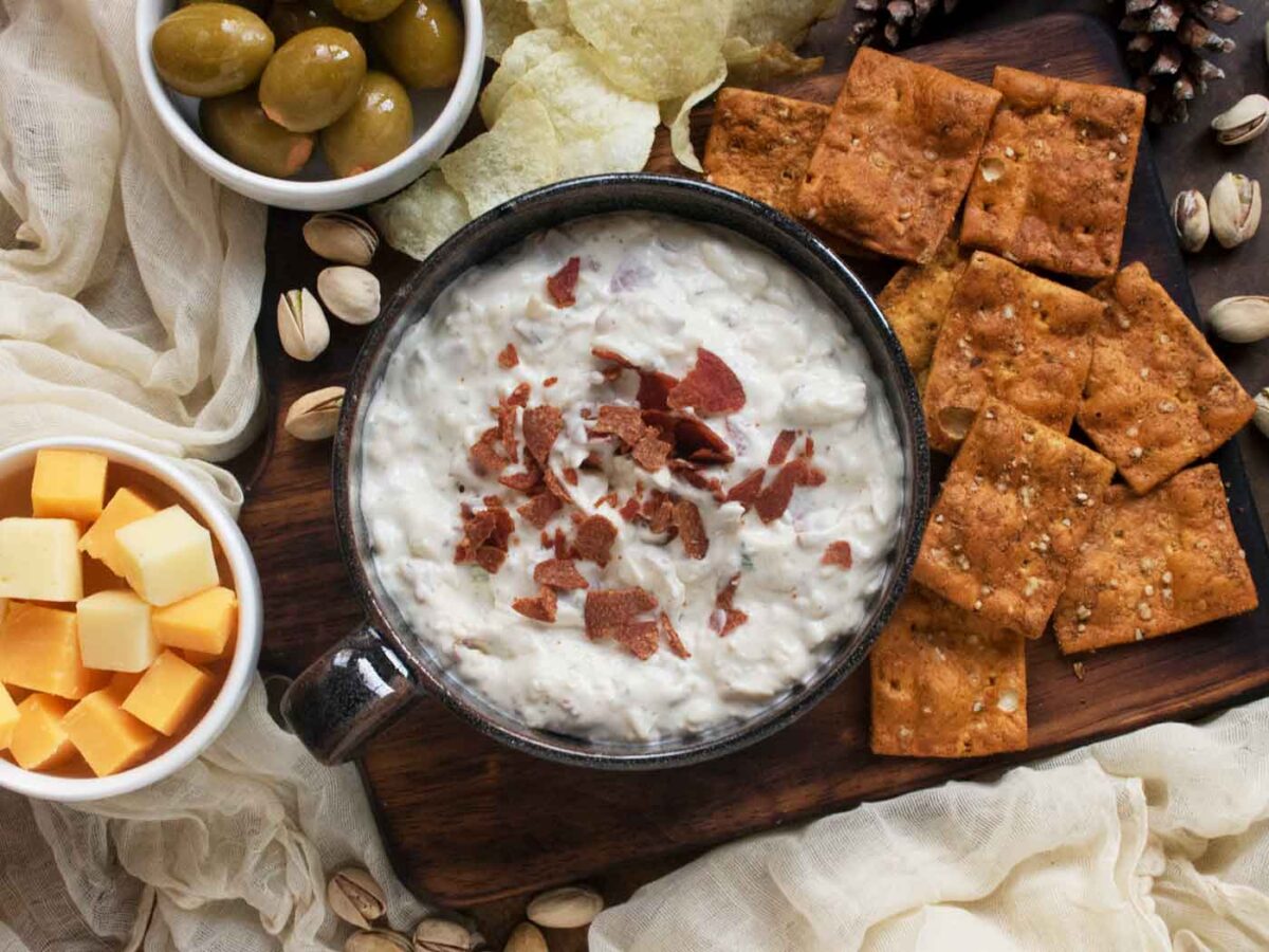 Overhead view of a bowl of Crispy Pepperoni Ranch Dip surrounded by charcuterie and crackers.