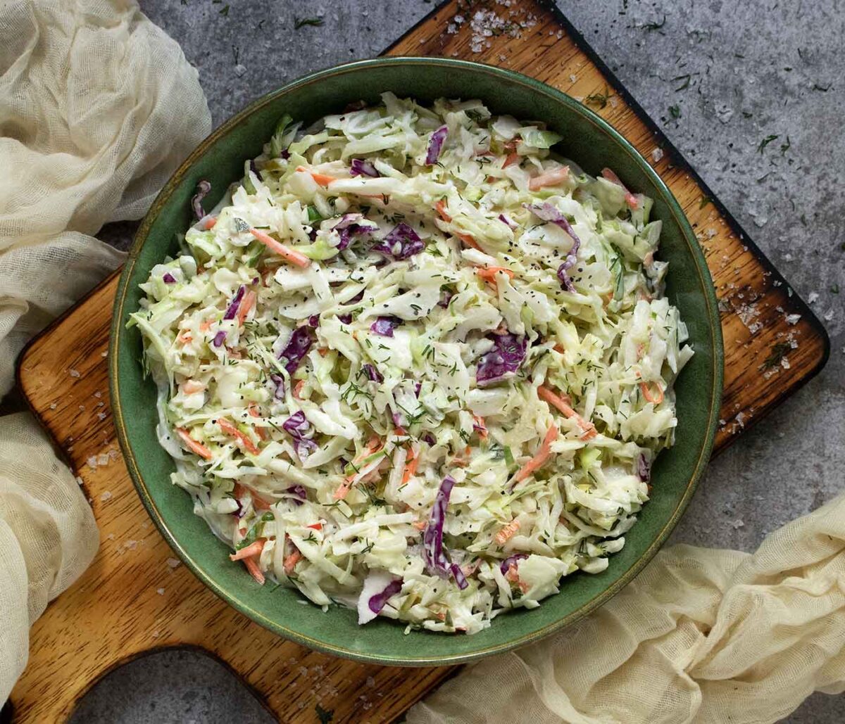 Overhead view of Pickle de Gallo Coleslaw in a green bowl, set on a wooden serving board.