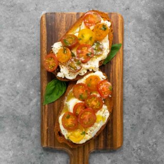 Two slices of Cherry Tomato Bruschetta on a wooden board.
