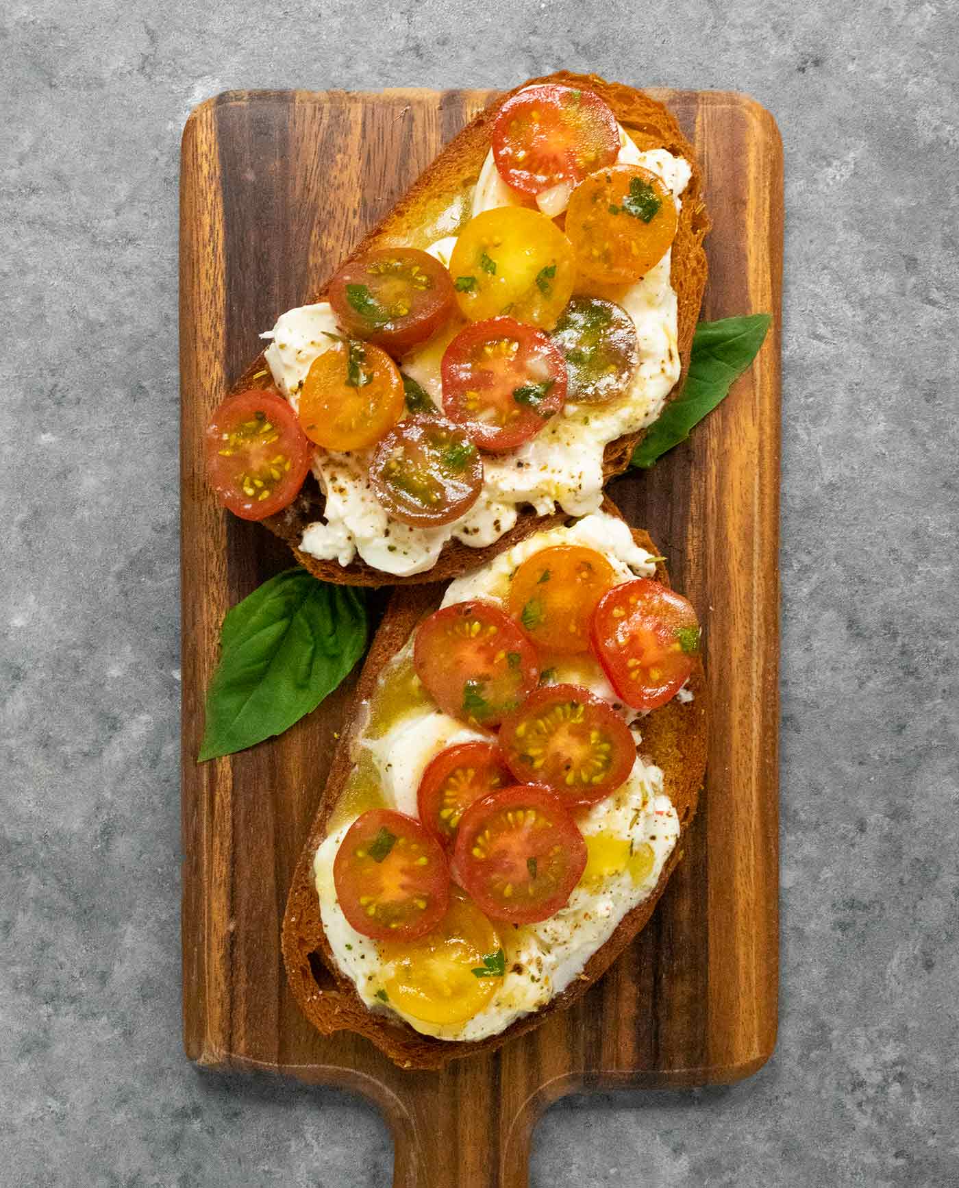 Overhead view of tomato bruschetta on a bread board.