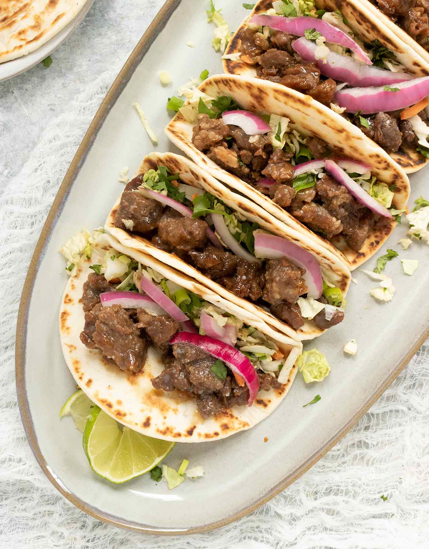 Four Korean BBQ Beef Tacos lined up on a platter.