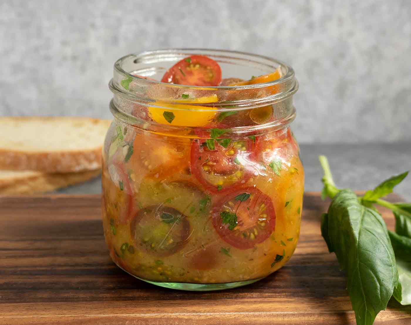 A mason jar filled with sliced cherry tomatoes in an olive oil vinaigrette.