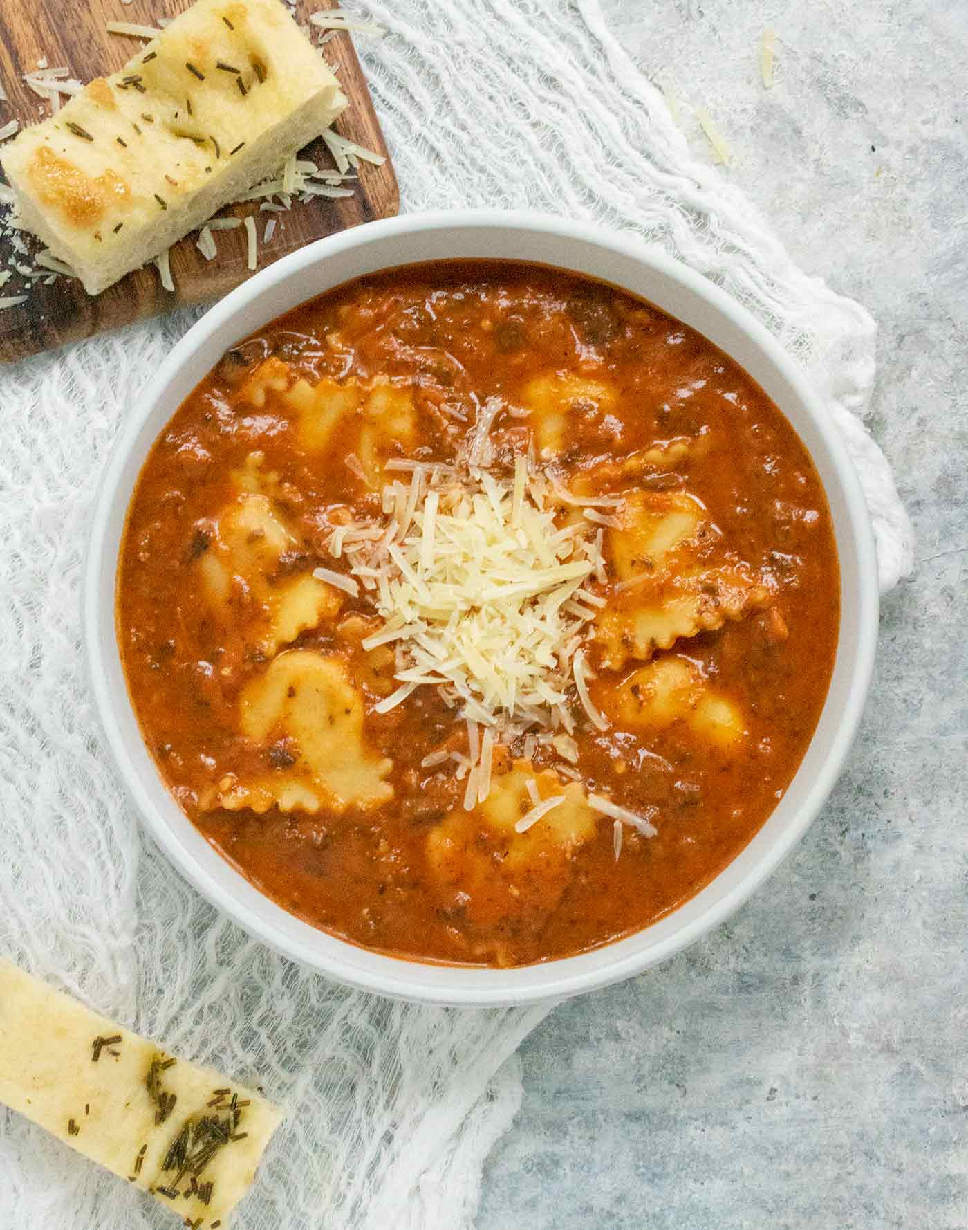 A bowl of Ravioli Soup with a side of focaccia slices.