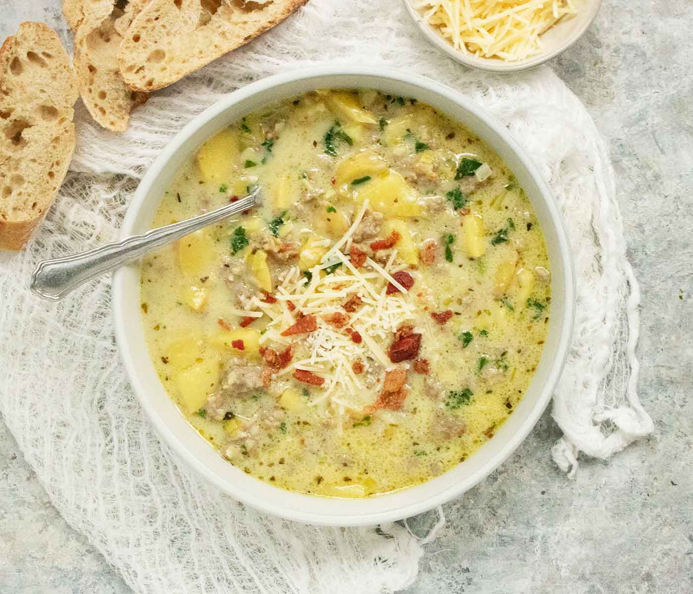 Overhead view of Tuscan Potato Soup in a light gray bowl with a spoon.