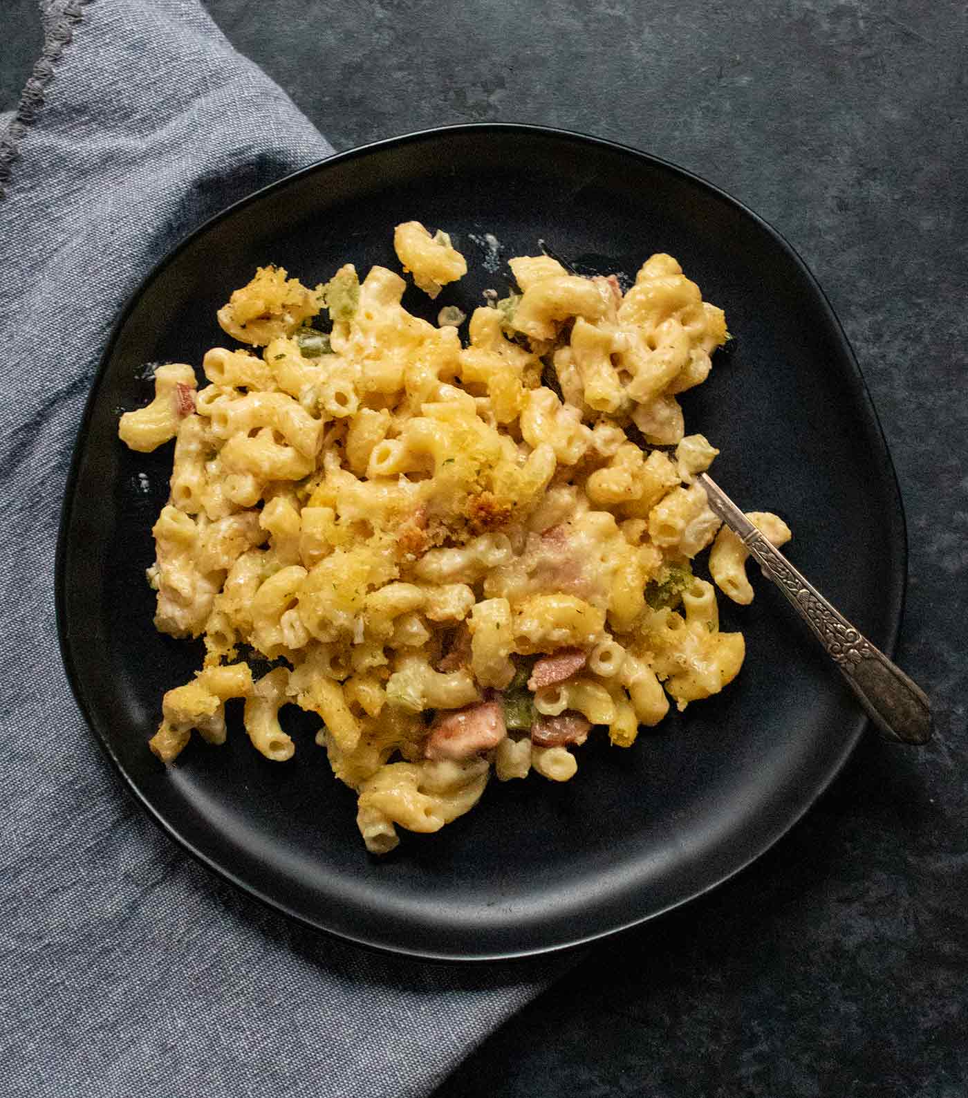 Cajun Mac and Cheese on a black plate with a fork.