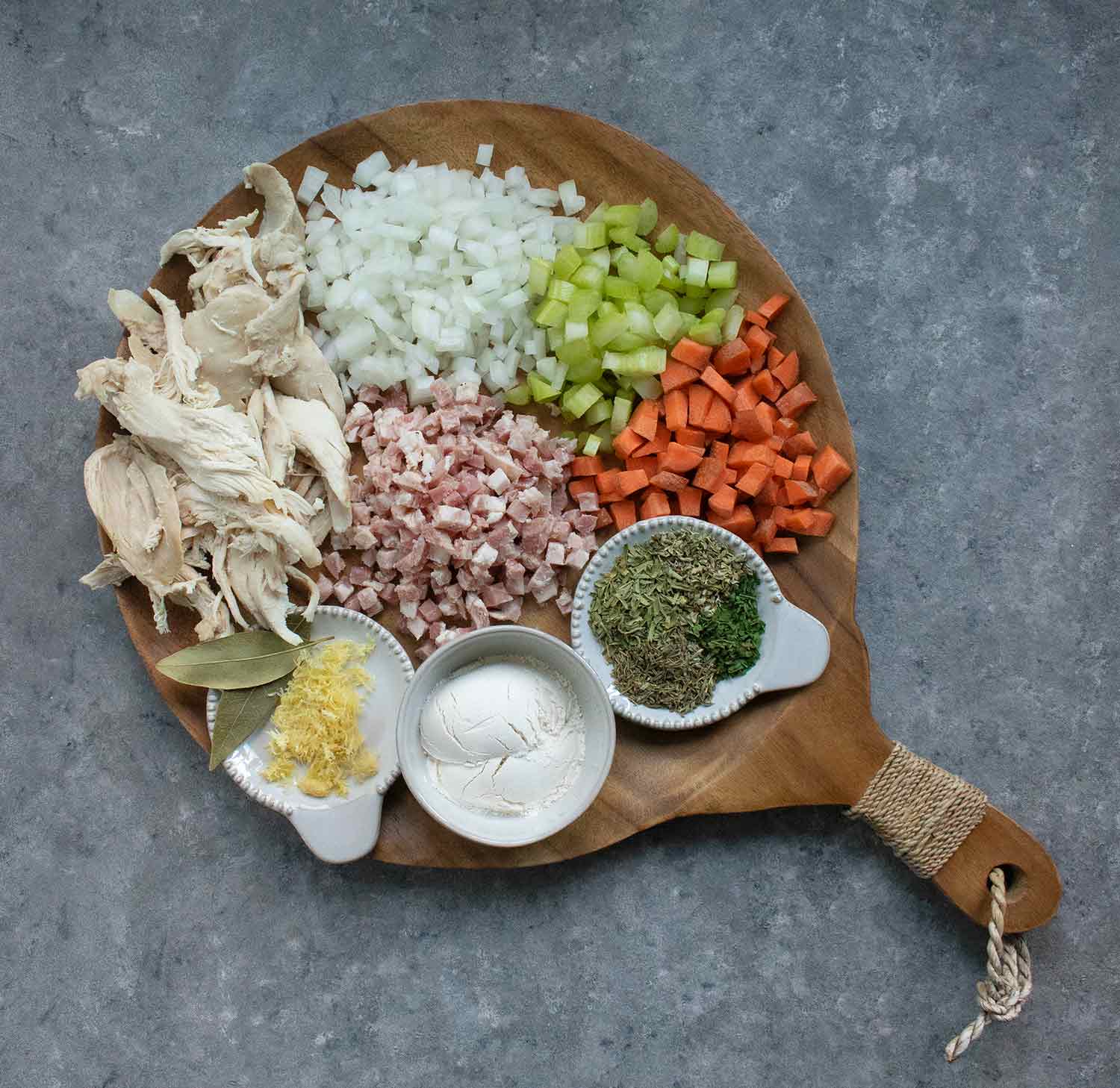 Ingredients for Creamy Chicken Noodle Soup arranged on a wooden serving board.