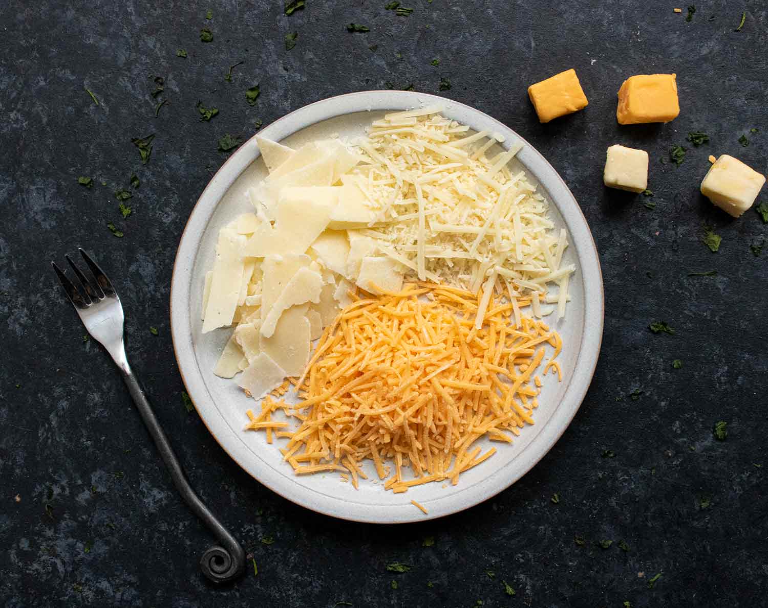 Shredded cheeses on a small plate.