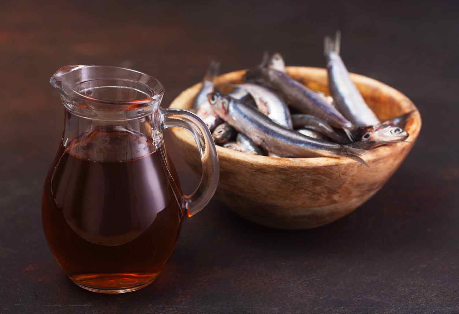 A small vessel of fish sauce and a bowl of whole anchovies.
