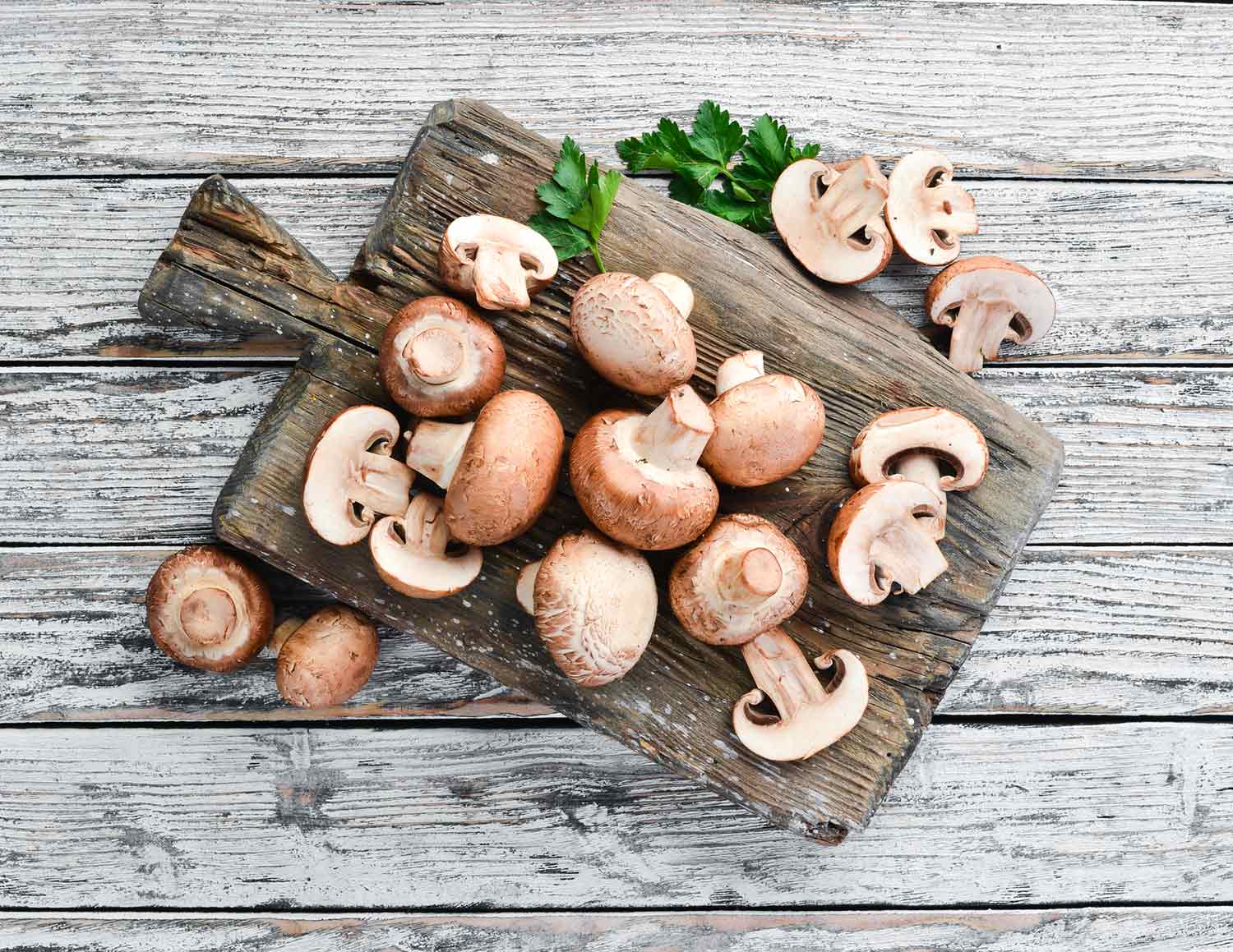 Cremini mushrooms on a wooden cutting board.
