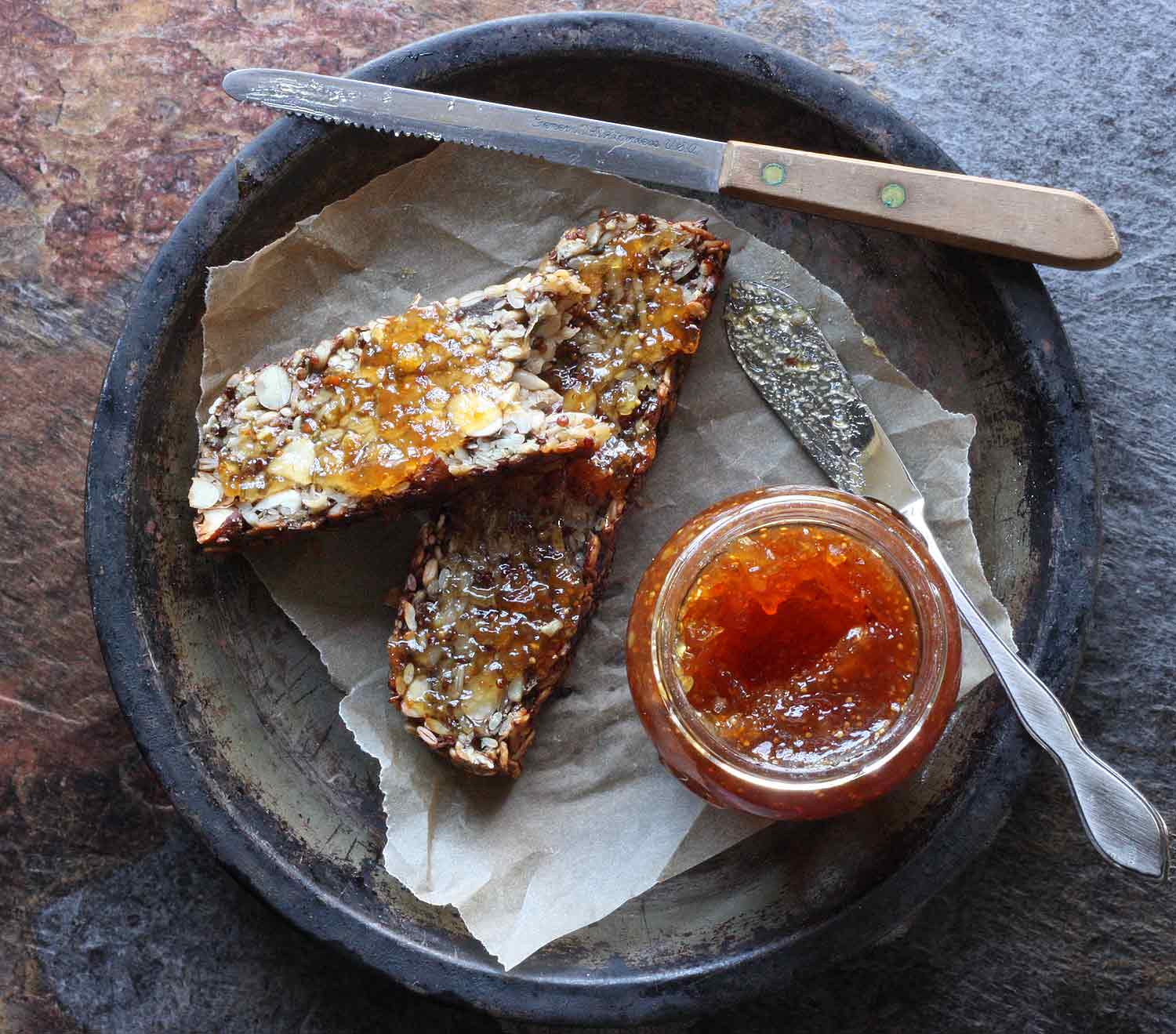 Two slices of Magic Seed and Nut Loaf spread with orange marmalade.