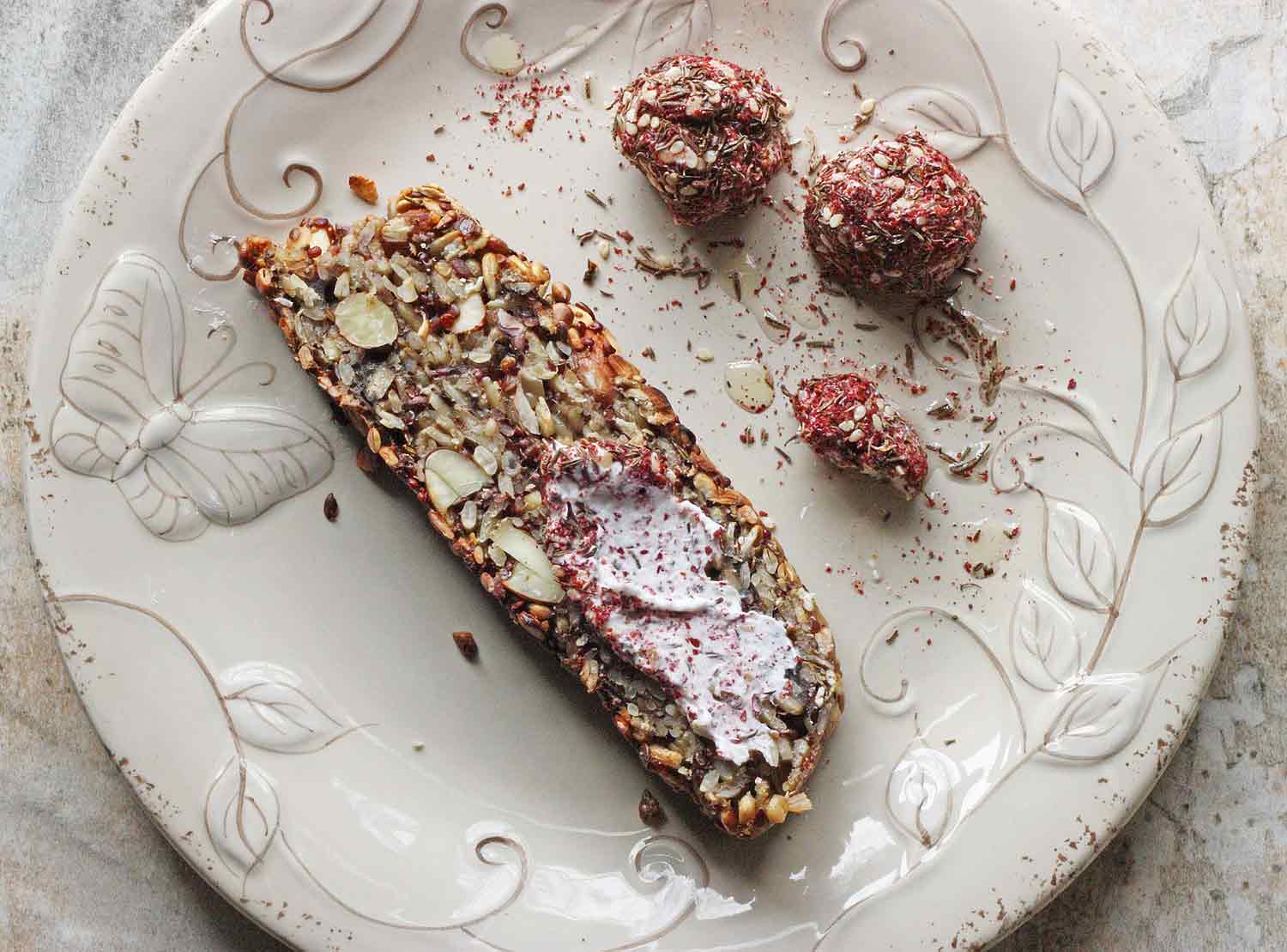 A slice of Seed & Nut Loaf spread with labneh and sprinkled with za'atar.