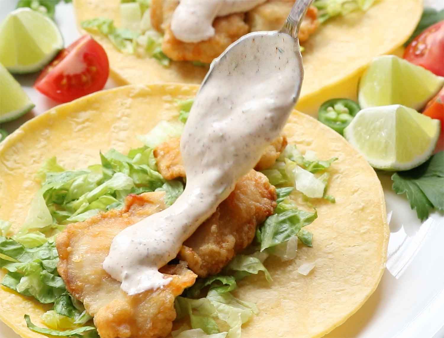 Spooning the fish taco sauce over a fish taco.