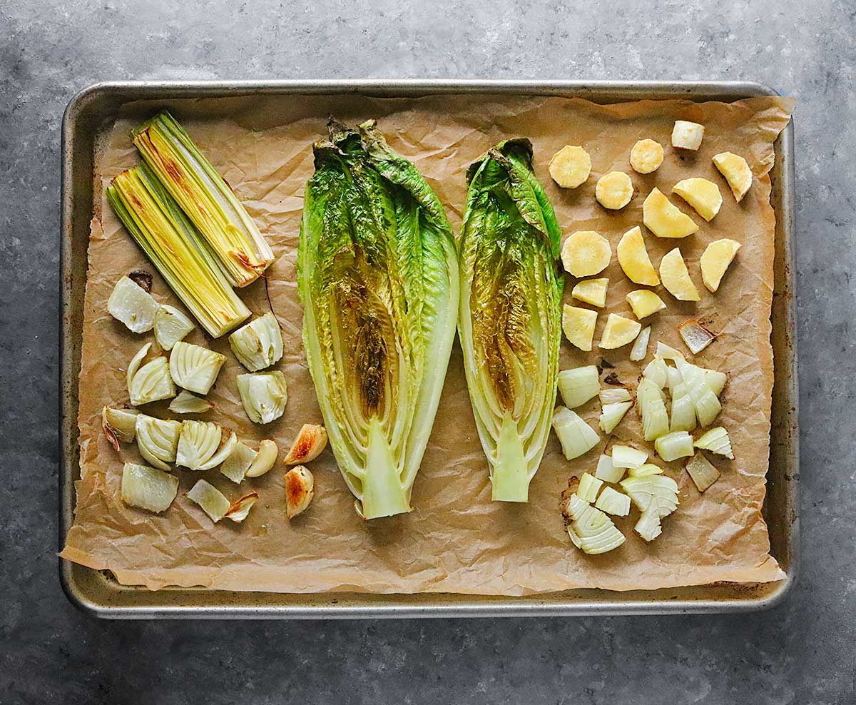 Roasted vegetables on a sheet pan, ready to be added to the soup pot.