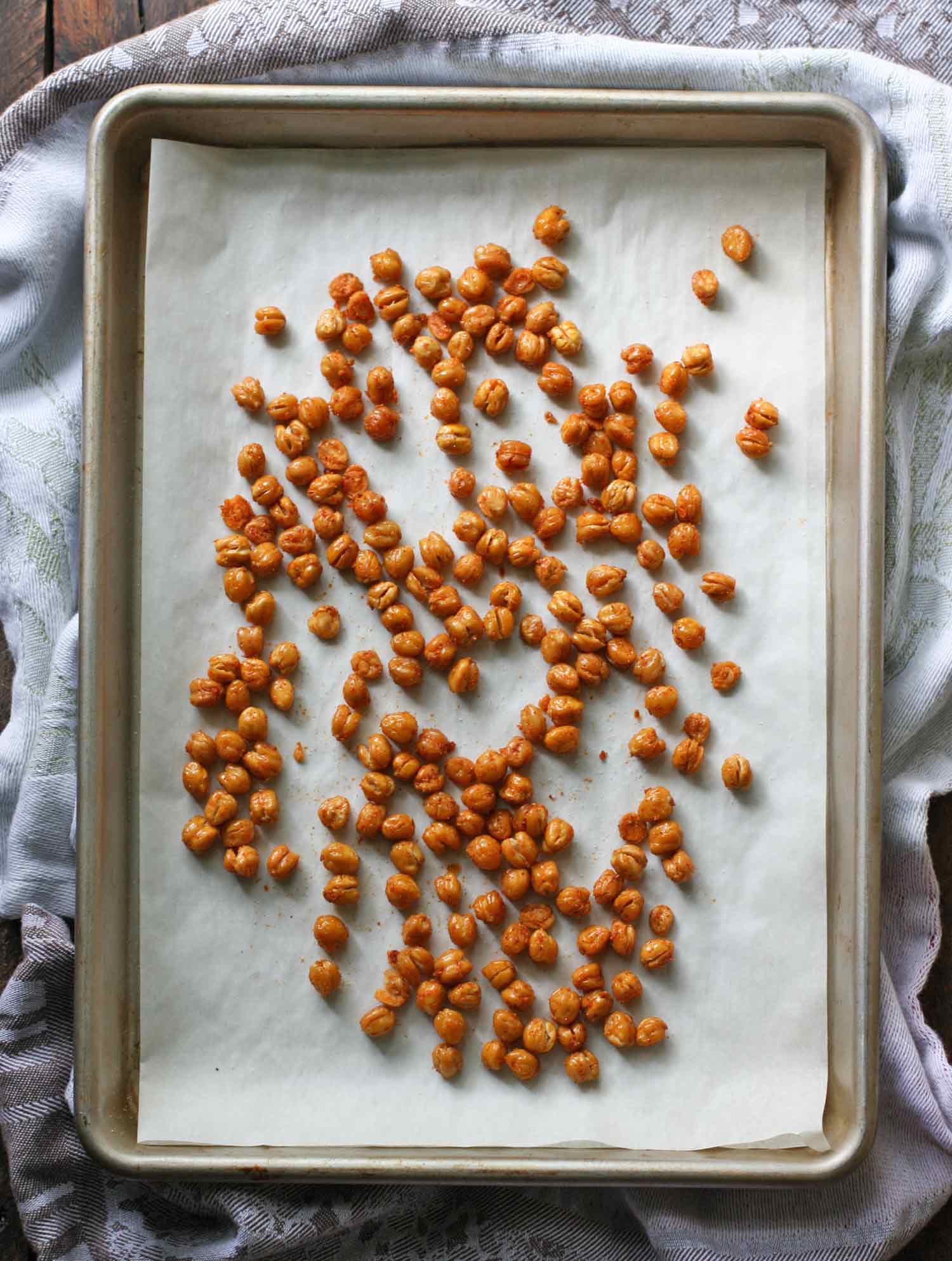 Crispy Oven Roasted Chickpeas spread out on a baking sheet.