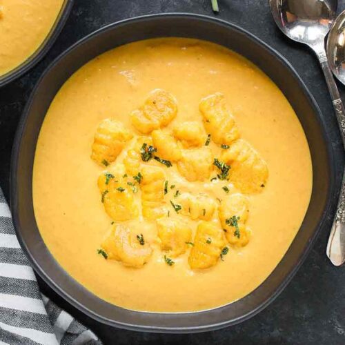 Creamy Pumpkin Soup in a black bowl topped with Pumpking Gnocchi.