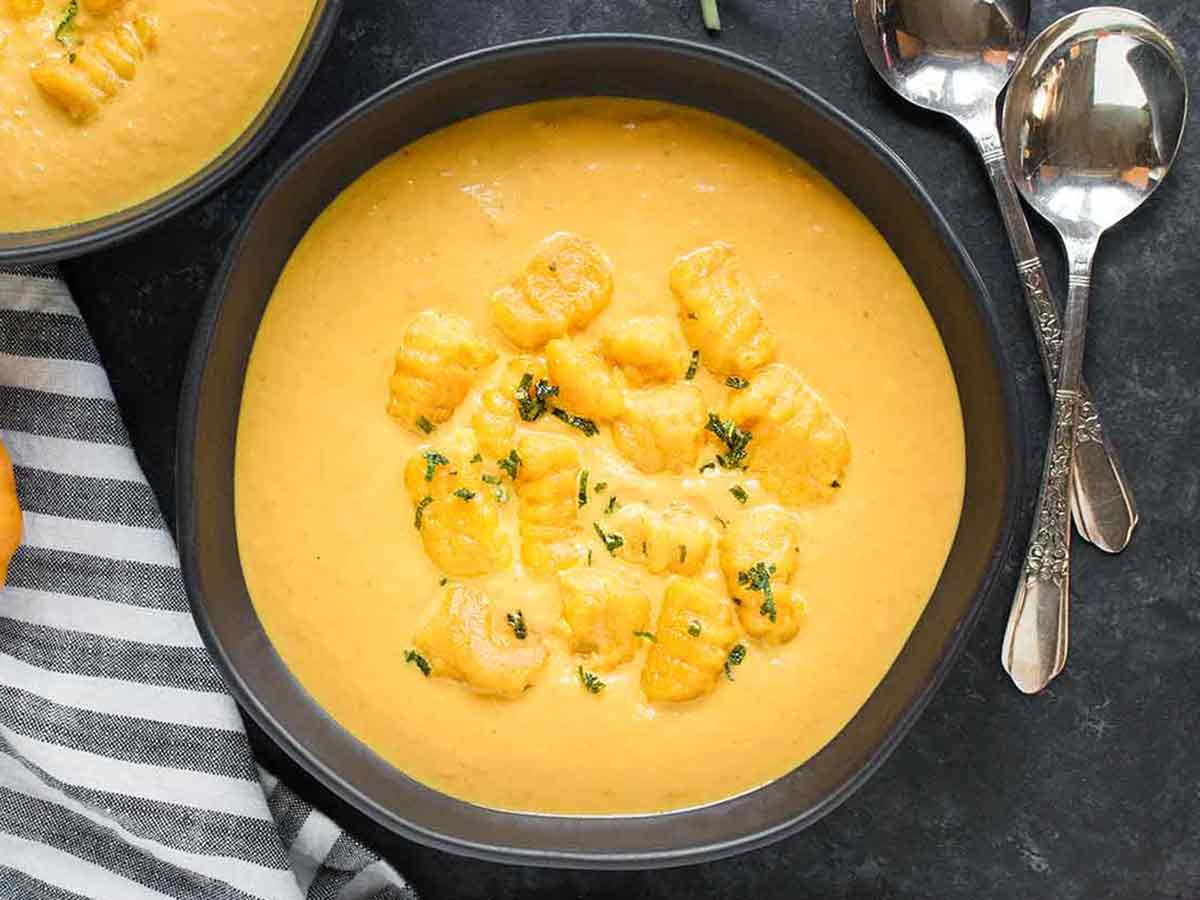 Creamy Pumpkin Soup in a black bowl topped with Pumpking Gnocchi.