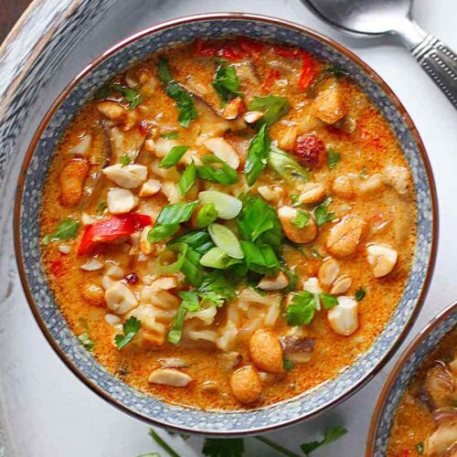 Vegetarian Thai Peanut Soup in a bowl on a white wooden serving tray.