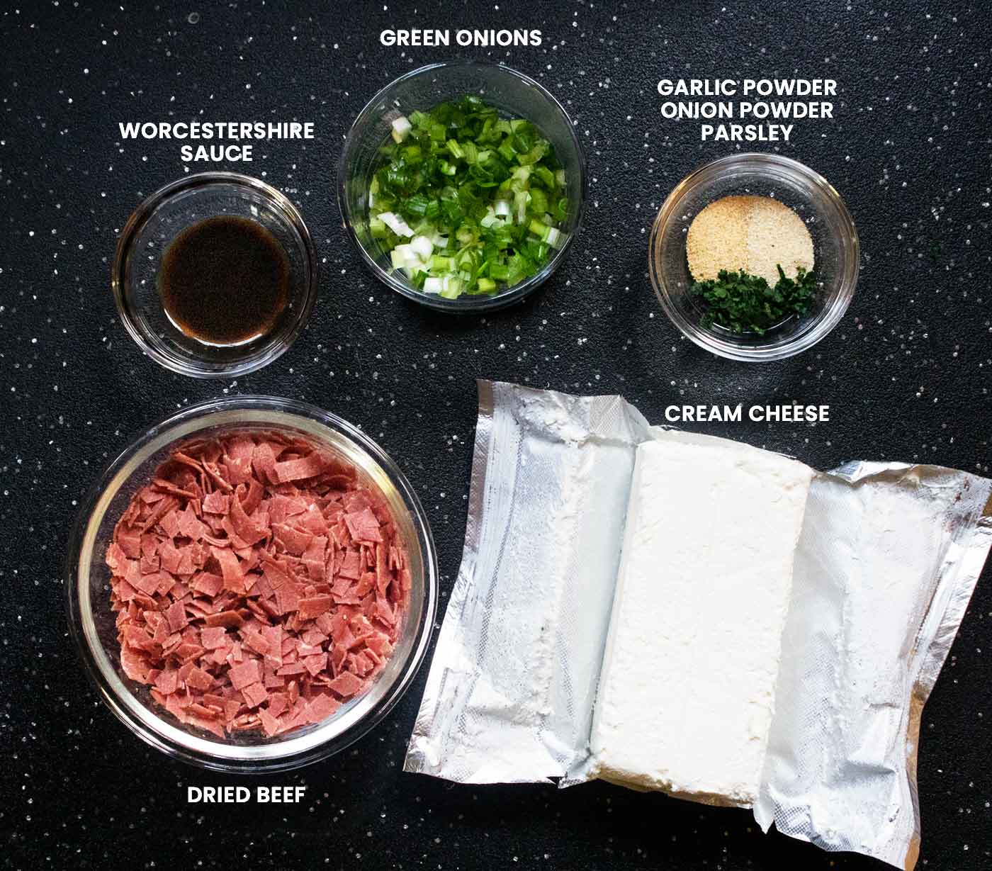 Prepped ingredients measured into small bowls and arranged on a black cutting board.