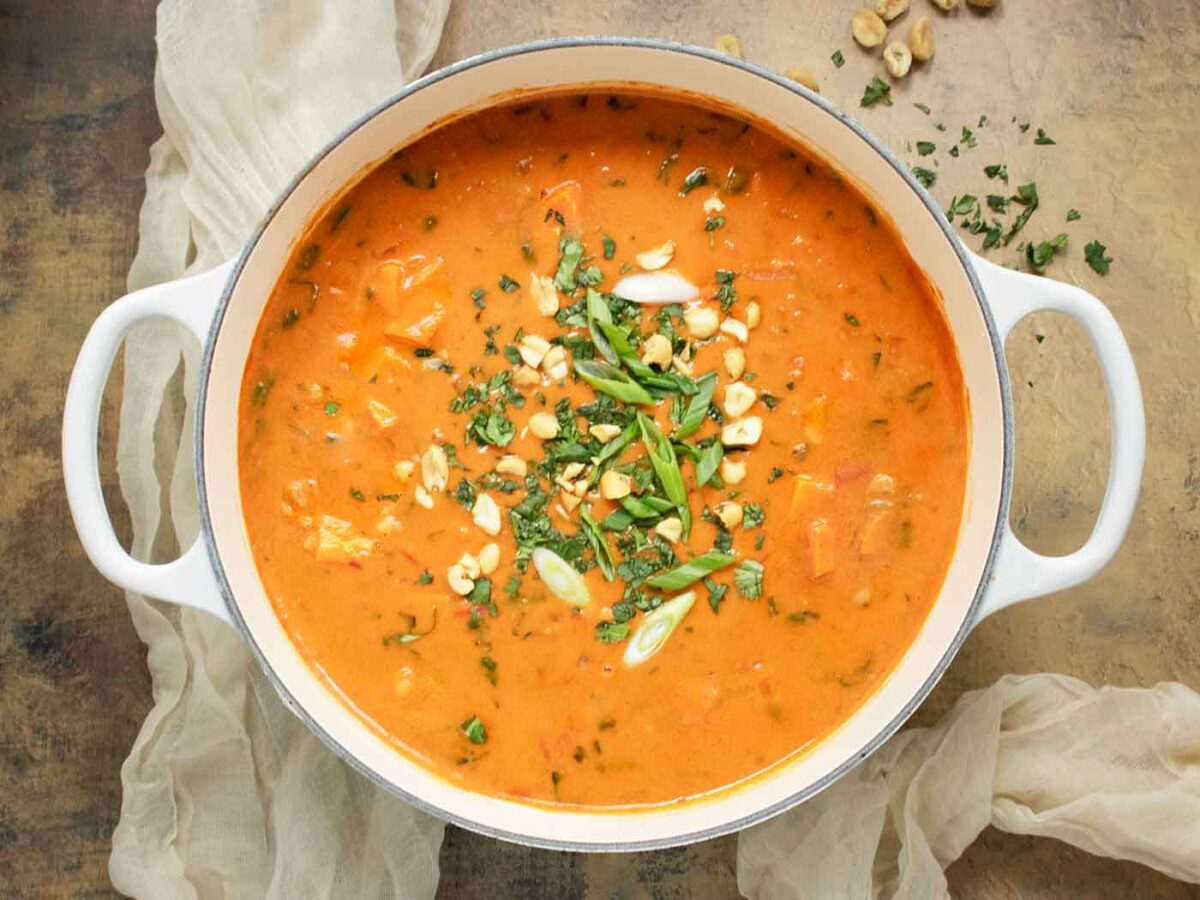 Overhead view of West African Peanut Soup in a large white Dutch oven.