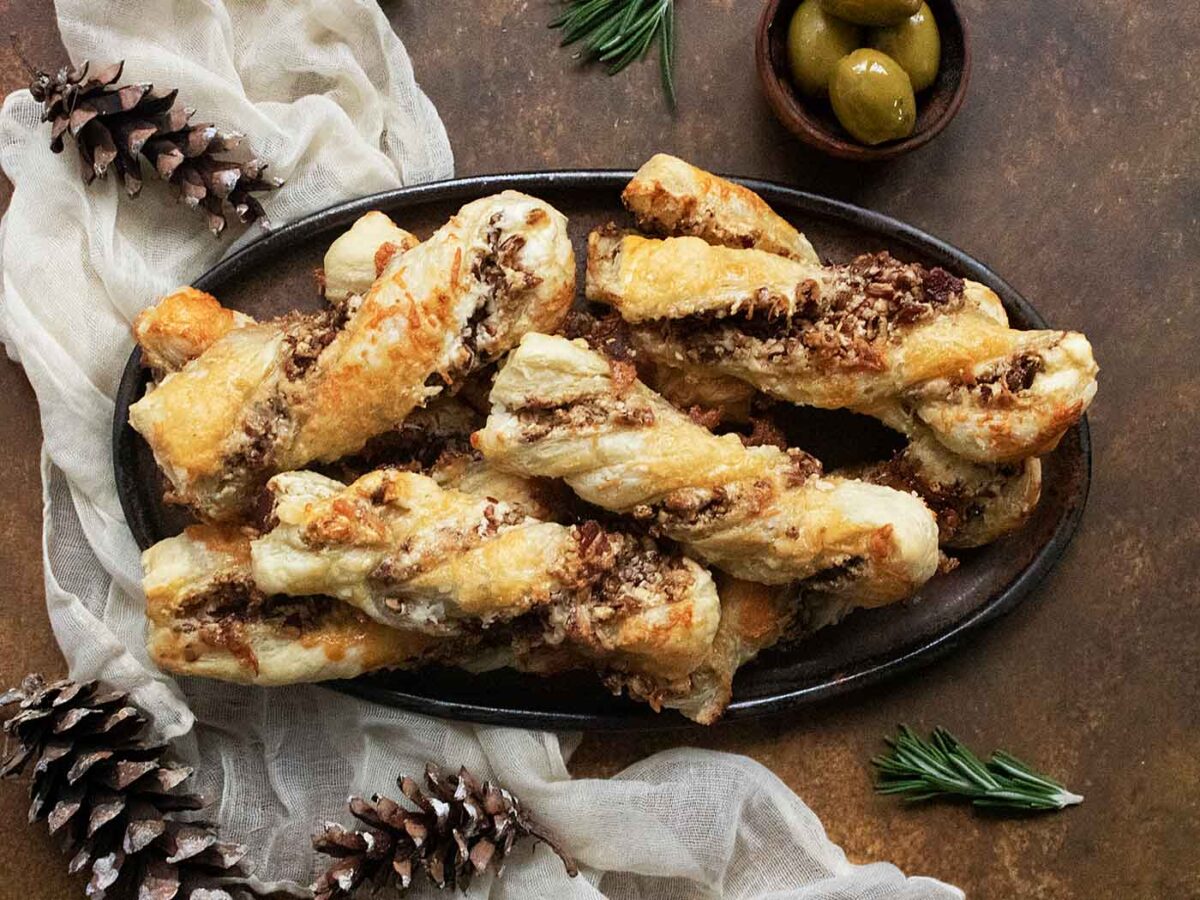 Overhead view of a stack of Cheesy Candied Bacon Twists on an oval platter.