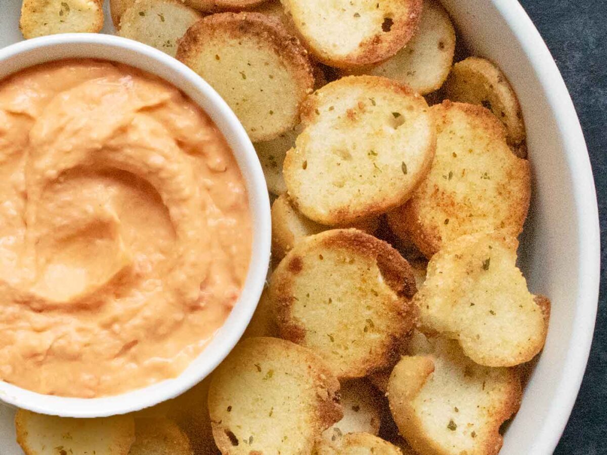 A close-up of a bowl of homemade bagel chips and a bowl of hummus.