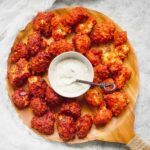 Two flavors of Sweet and Spicy Cauliflower Bites on a serving tray with dip.