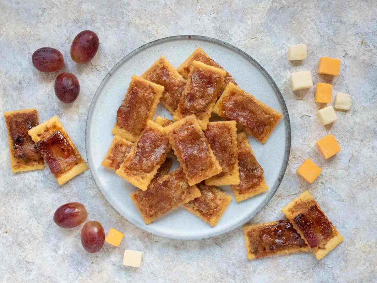 Bacon Crackers on a plate with a side of grapes and cheese cubes.