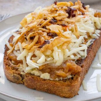 Close-up of an angled side view of one Cheesy French Onion Fried Toast on a plate.