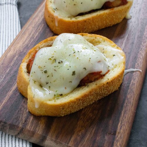 Side angled view of Meatballs on Texas Toast on a wooden board.