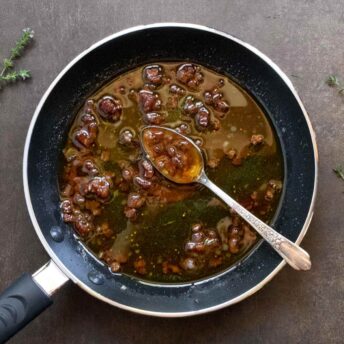 Warm Bacon Balsamic Fig Vinaigrette in a skillet with a spoon.