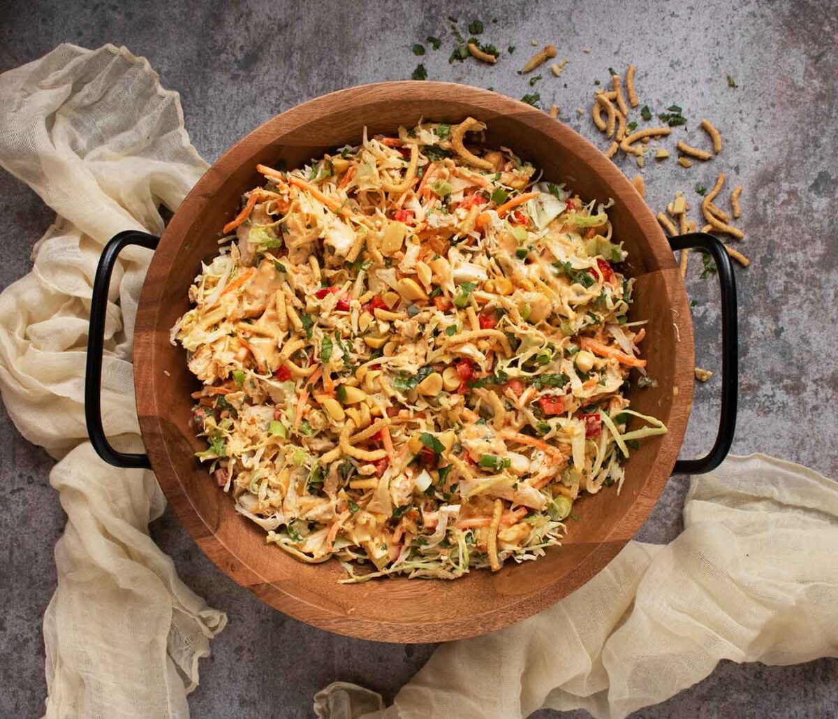 Overhead view of Chili Crisp Chopped Chicken Salad in a wooden salad bowl with metal handles.