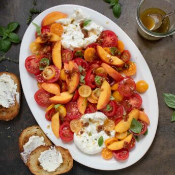 Tomato Peach Burrata Salad on a white oval platter.