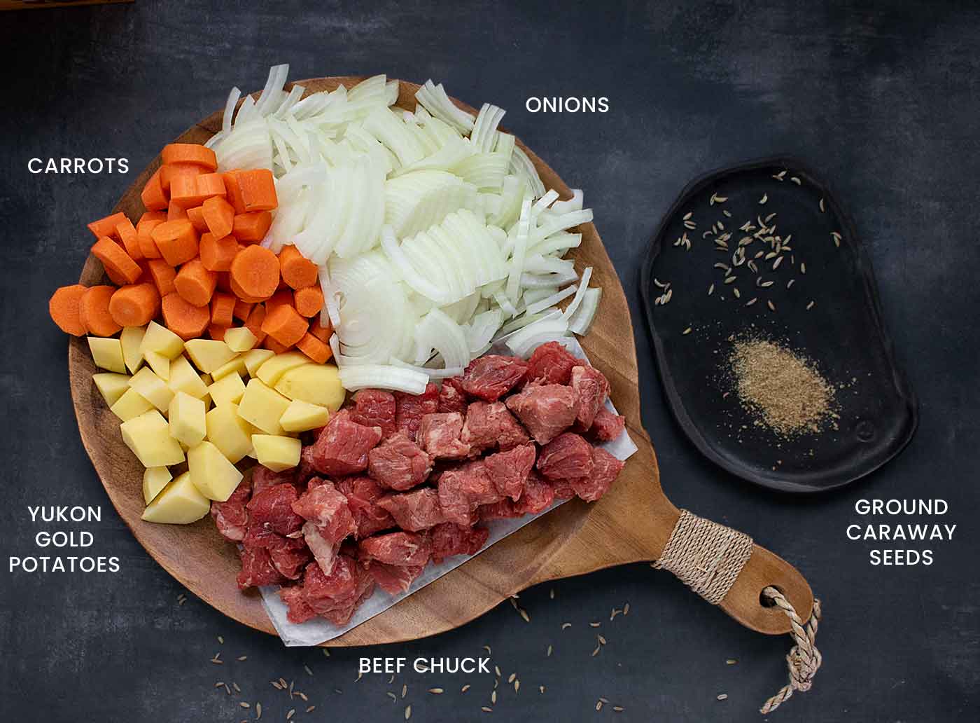 Ingredients to be prepped for Austrian Hungarian Goulash on a wooden board.