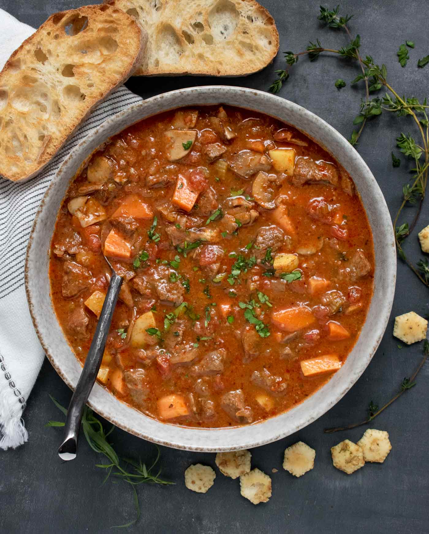 Overhead view of Braised Vegetable Beef Soup in a bowl with a spoon.