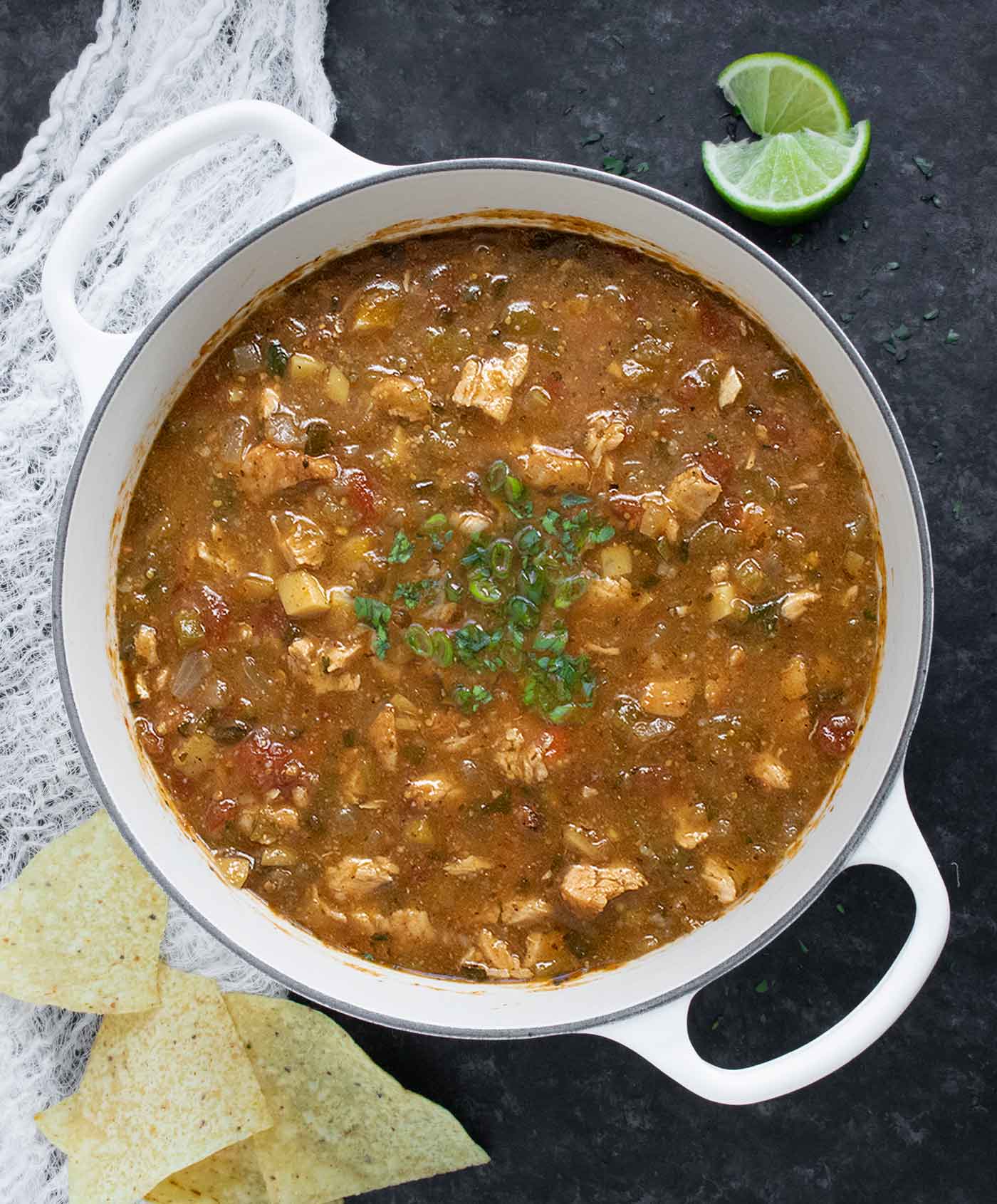 Overhead view of Chile Verde Tortilla Soup in a white Dutch oven.