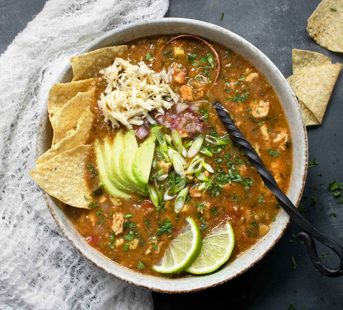 A bowl of Chile Verde Tortilla Soup with lots of yummy toppings.