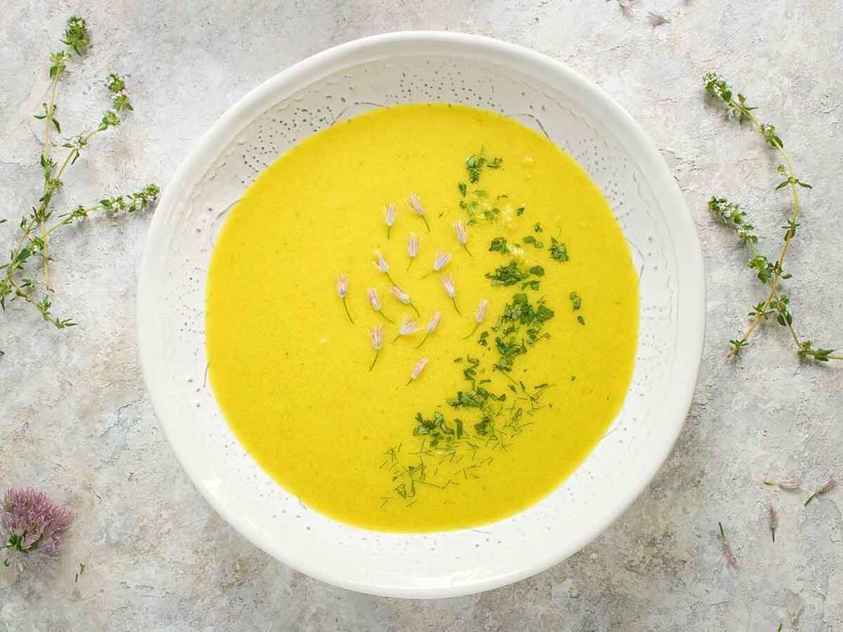 Overhead view of bright and glowy Spring Cauliflower Fennel Soup in a white bowl.