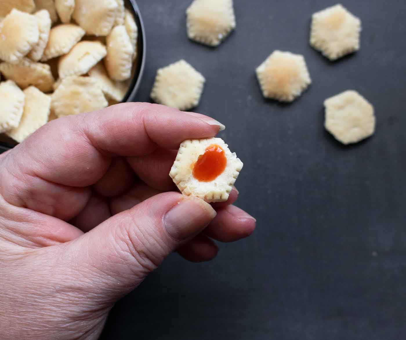 Close up of an oyster cracker with a drop of hot sauce in the middle.