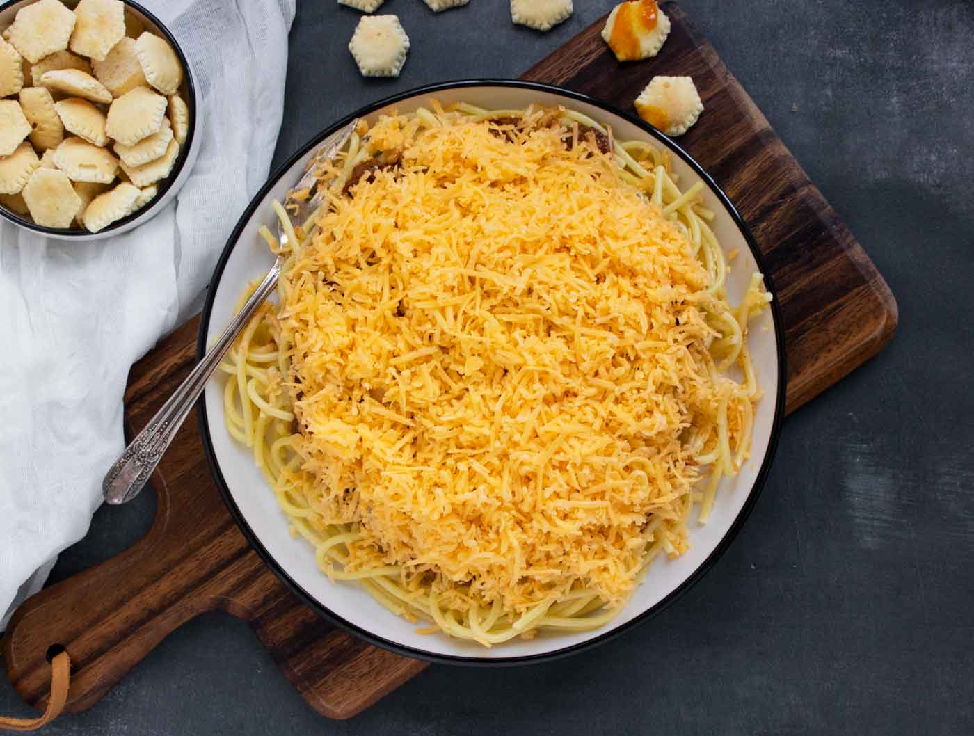 Cincinnati Chili, a 5-way on a plate on a serving board with oyster crackers.