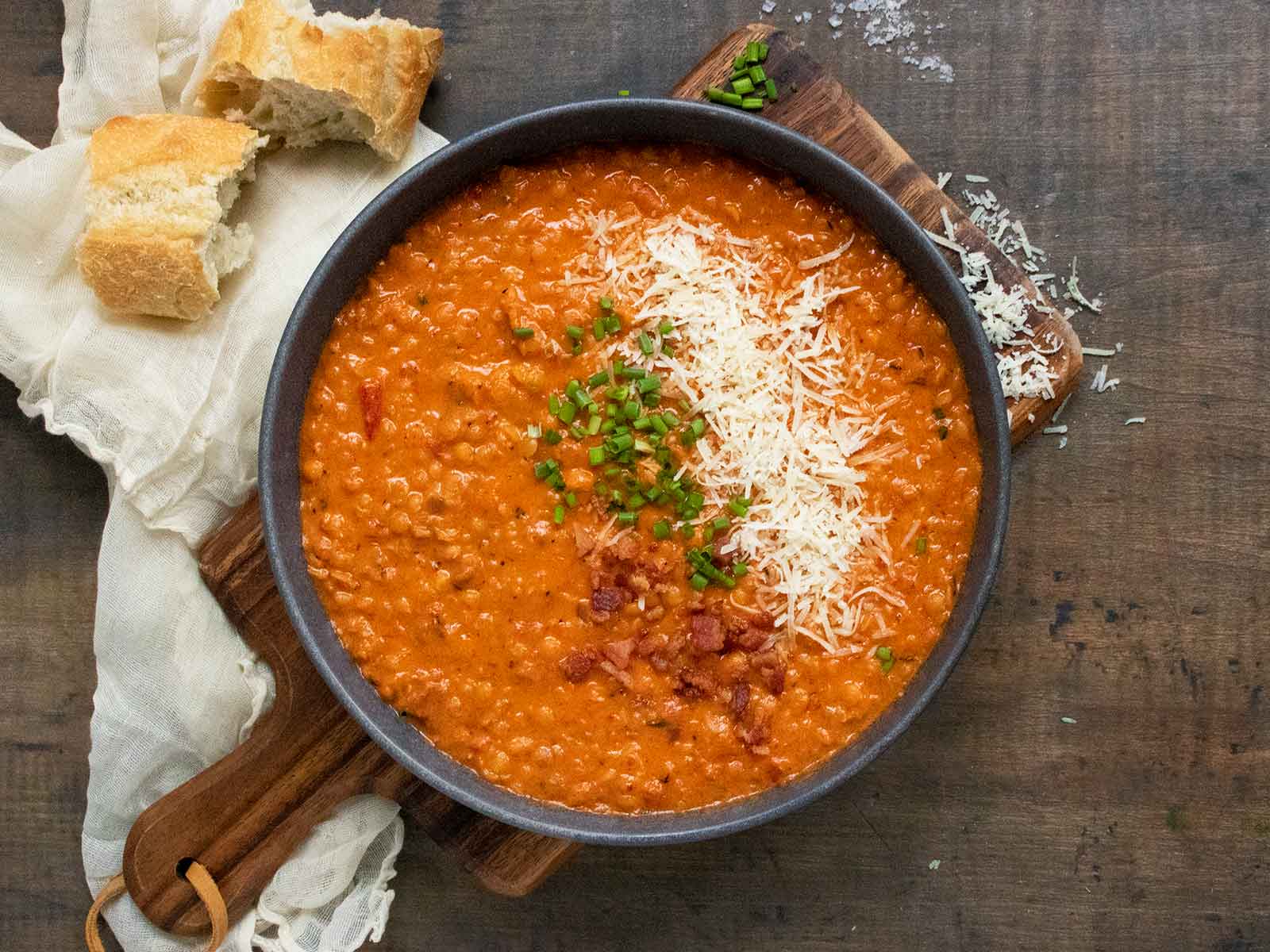 A bowl of Marry Me Red Lentil Soup on a wooden cutting board.