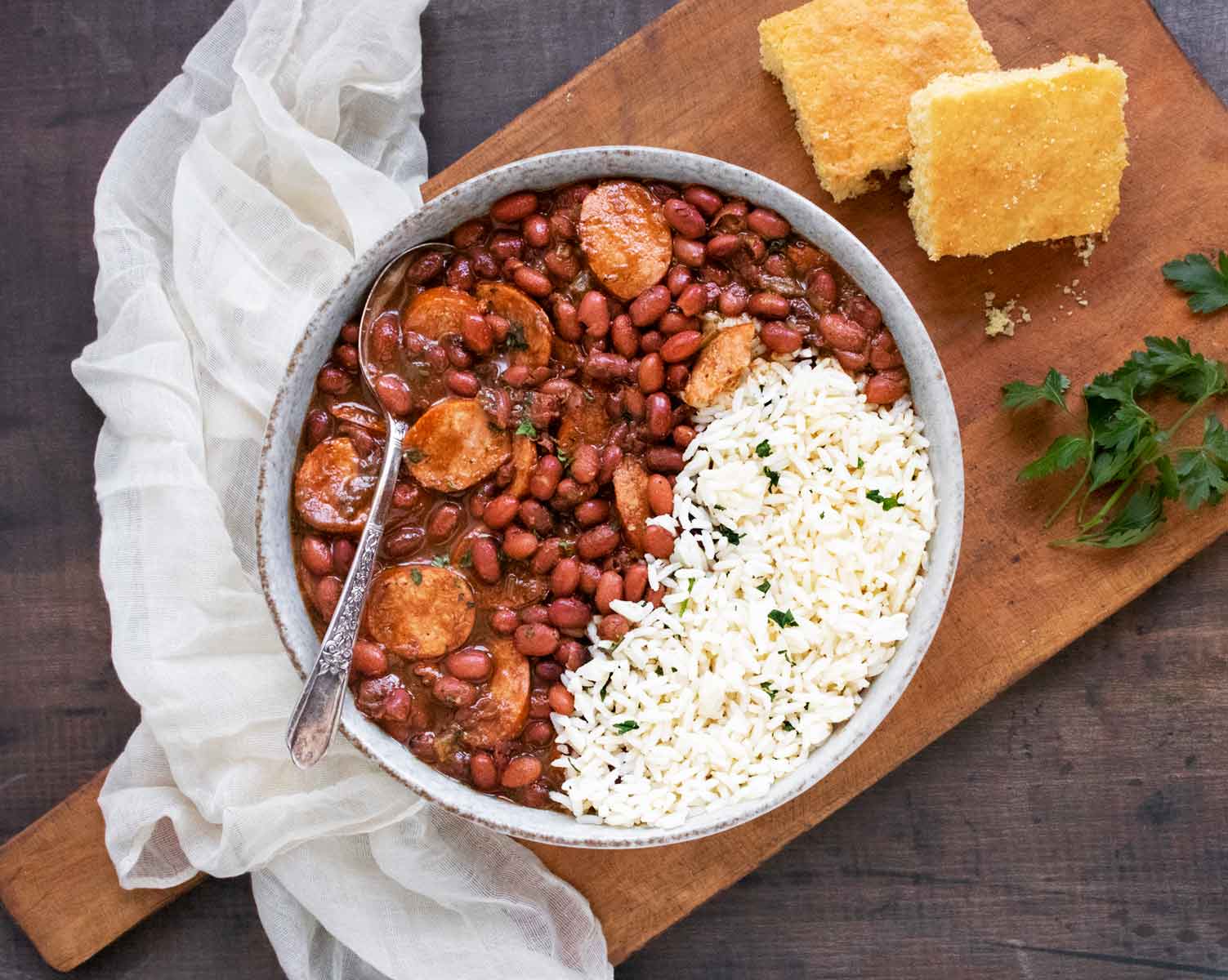 An overhead shot of Red Beans and Rice in a bowl on a wooden board, with cornbread on the side.