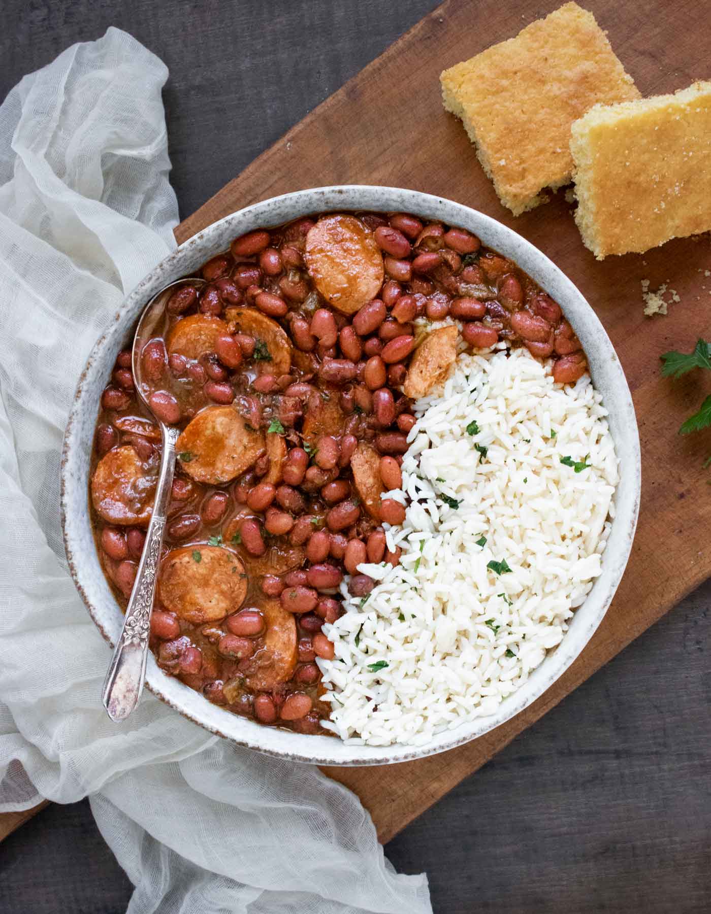 Overhead view of Red Beans and Rice in a bowl with a spoon, and a side of cornbread.