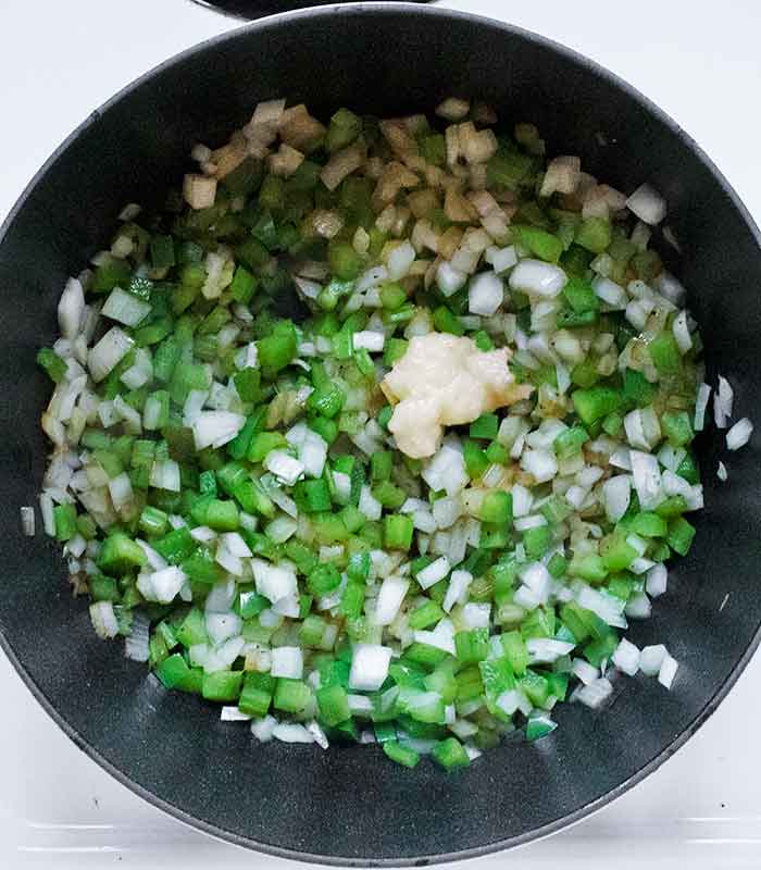 Adding garlic to the softened Holy Trinity of vegetables.