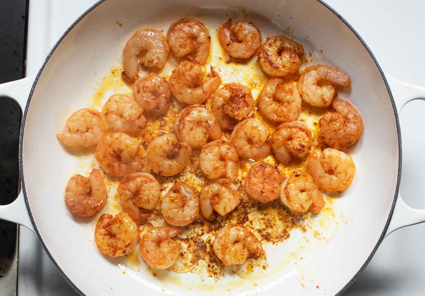 Seasoned shrimp sauteeing in a large skillet.