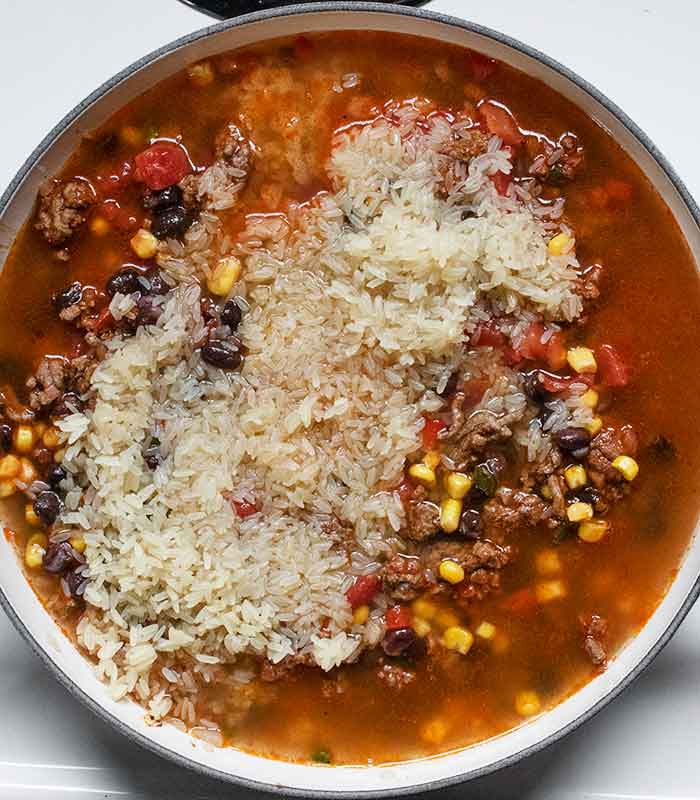 Adding the rice and broth to the pan.
